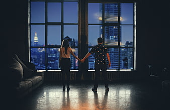 Couple holding hands looking at city skyline at night