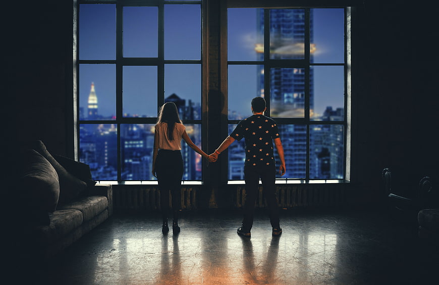 Couple holding hands looking at city skyline at night