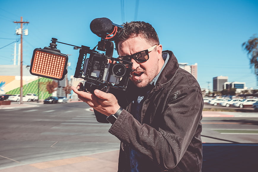 Filmmaker with Cinema Camera and LED Light on Street