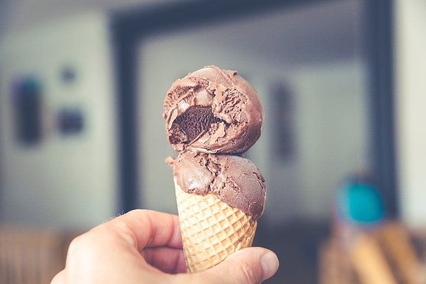 Hand holding chocolate ice cream cone with bite taken out