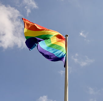 Rainbow Pride Flag Waving Against Blue Sky