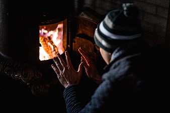 Man warming hands by wood stove fire in winter