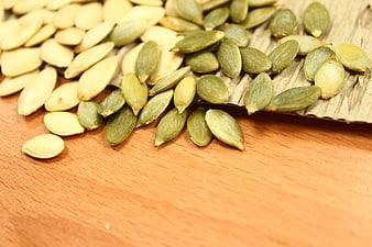 Pumpkin Seeds Spilling From Wooden Scoop On Wooden Surface