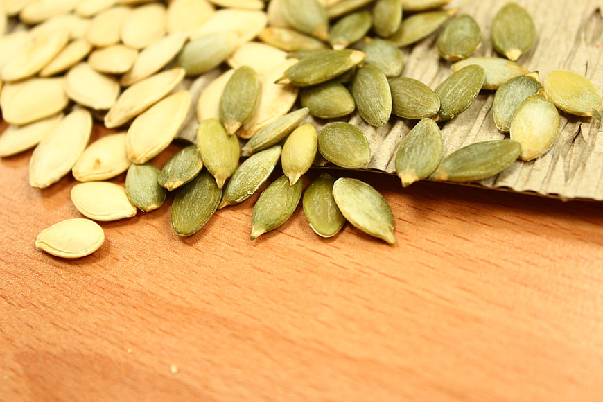 Pumpkin Seeds Spilling From Wooden Scoop On Wooden Surface