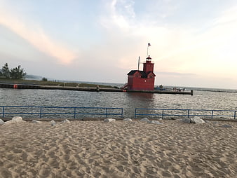 Red Lighthouse on Pier at Dusk with Sandy Beach Foreground