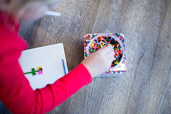 Child playing with colorful beads on wooden table