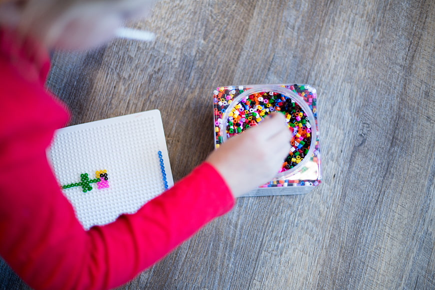 Child playing with colorful beads on wooden table