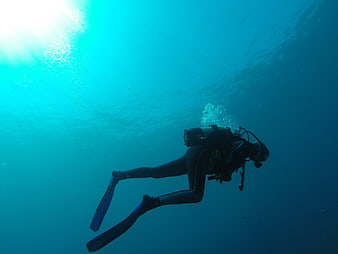 Scuba Diver Swimming Underwater in Blue Ocean Water