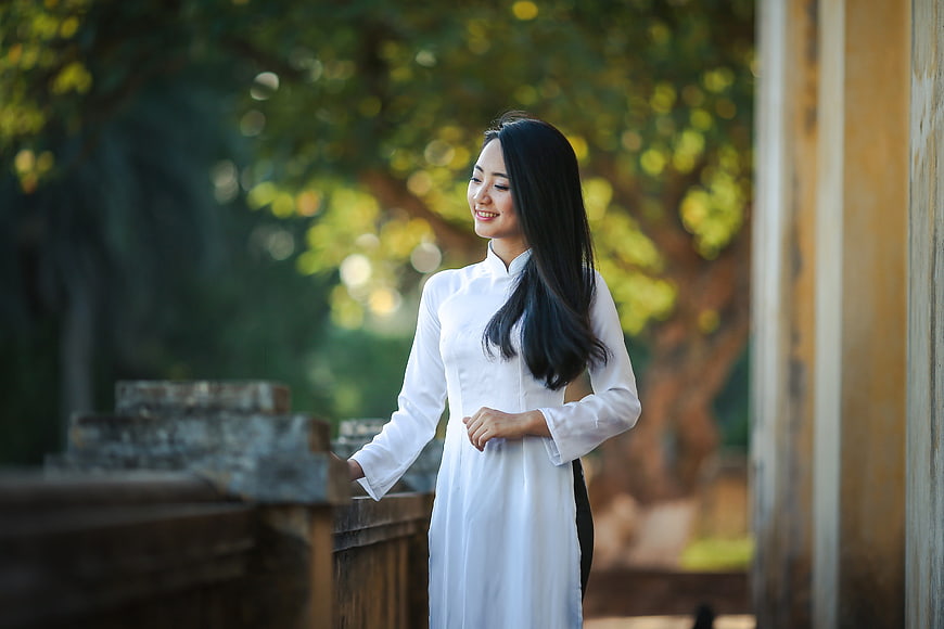Smiling Vietnamese Woman in Traditional White Ao Dai Outdoors