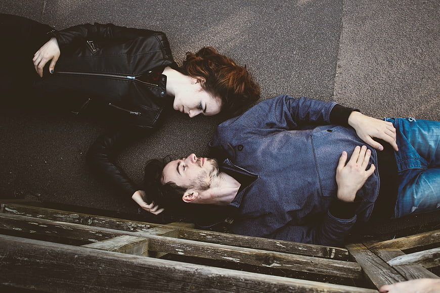 Couple lying on ground looking at each other from above