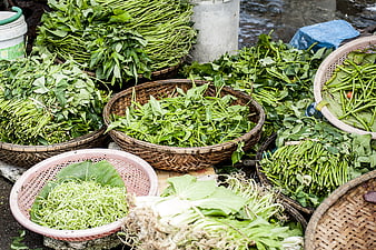 Fresh green vegetables in woven baskets at a floating market