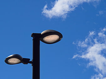 Modern street lamp against blue sky with clouds