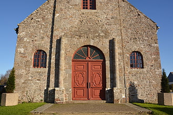Front view of old stone church with red wooden doors