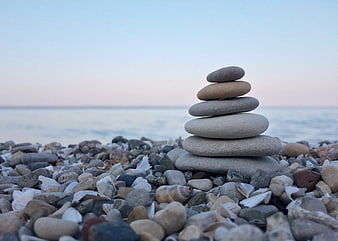 Stacked stones on pebble beach at sunset