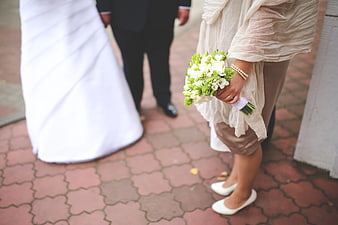Bridesmaid holding white and green bouquet at wedding ceremony