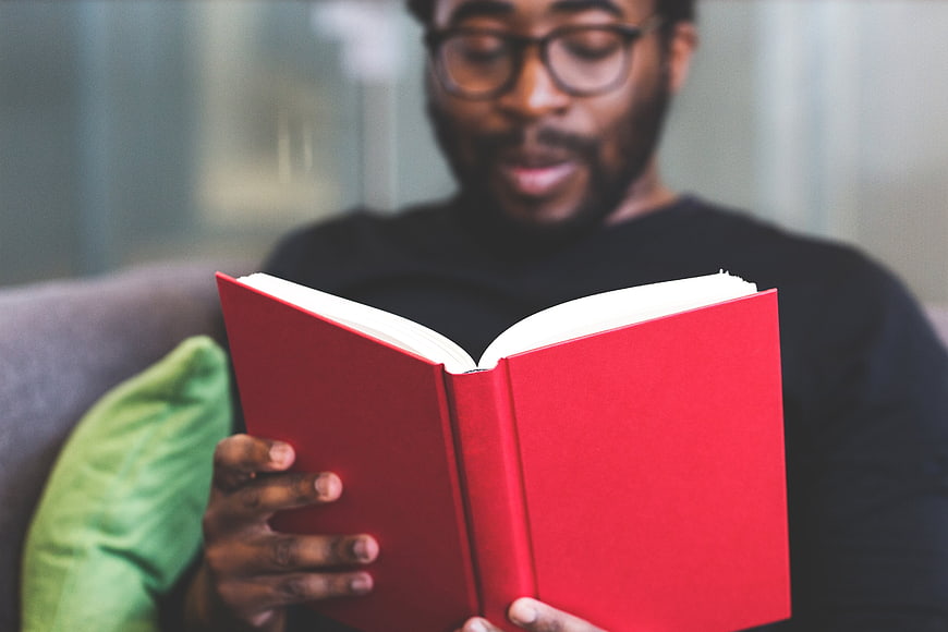 Man Reading Red Book on Couch