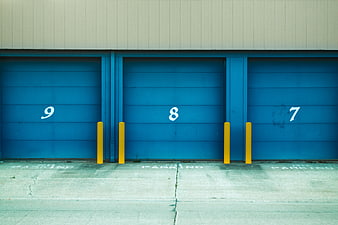 Blue industrial garage doors with yellow bollards and parking numbers