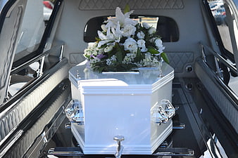 White Coffin with Flowers in Luxury Hearse Interior