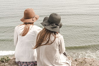 Two Women in Hats Sitting by the Ocean