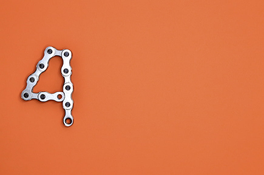 Metal bicycle chain forming the number four on an orange background