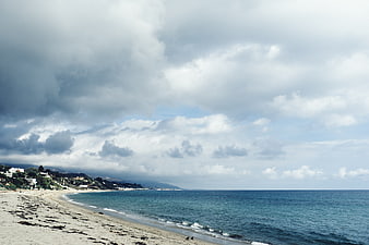Dramatic cloudy sky over sandy beach and blue ocean coastline