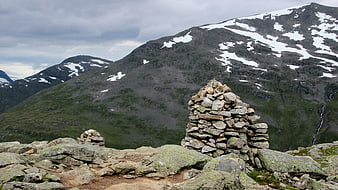 Mountain Cairn with Snowy Peaks and Overcast Sky