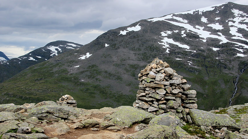 Mountain Cairn with Snowy Peaks and Overcast Sky