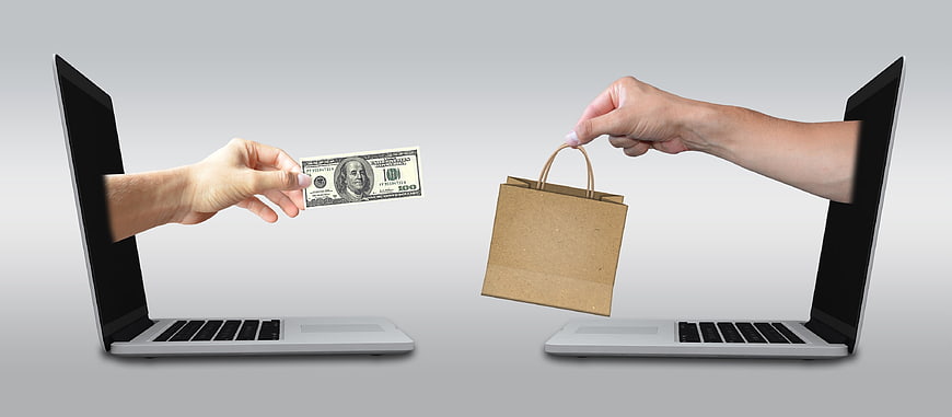 Online Shopping Concept with Hands Exchanging Money and Bag from Laptops