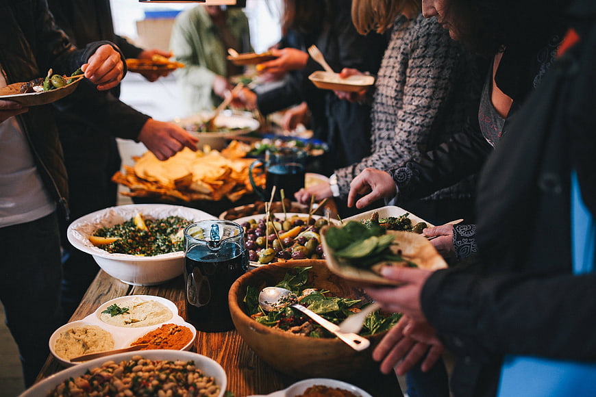 People serving themselves at a healthy buffet table