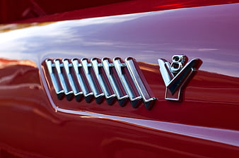 Close-up of Chrome V8 Emblem on Red Car Hood