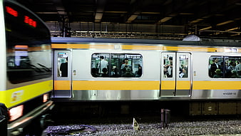 Passengers on a yellow and silver commuter train at a station