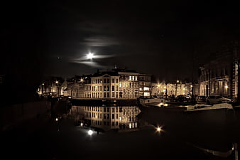 Night cityscape with canal reflections and moonlight