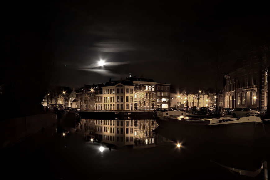 Night cityscape with canal reflections and moonlight