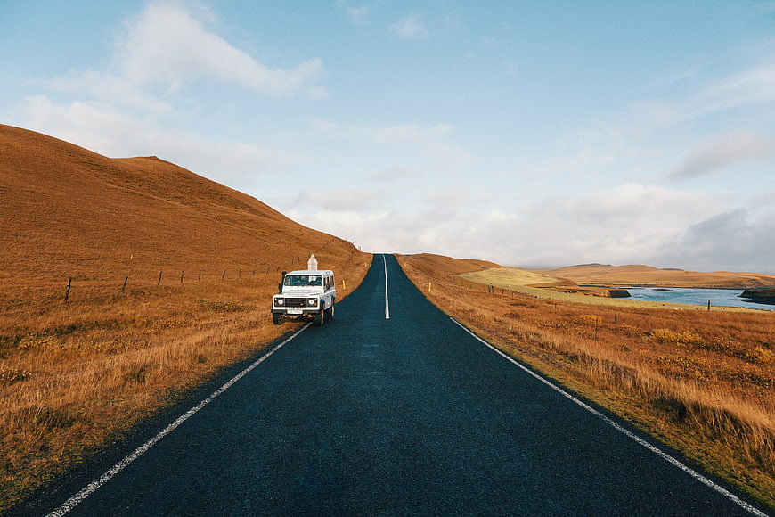 White SUV on scenic road through golden highlands