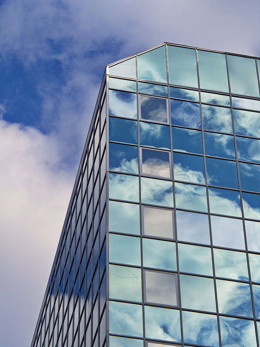 Modern Glass Skyscraper Reflecting Blue Sky and Clouds