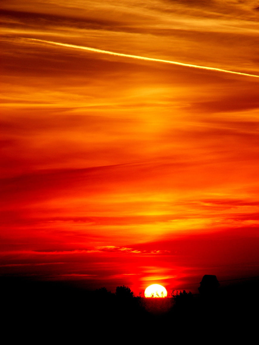 Vibrant Red Sunset Sky With Silhouetted Horizon And Sun