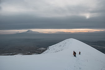 Hikers on Snowy Mountain Ridge at Sunset