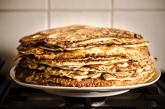 Stack of golden homemade pancakes on a white plate