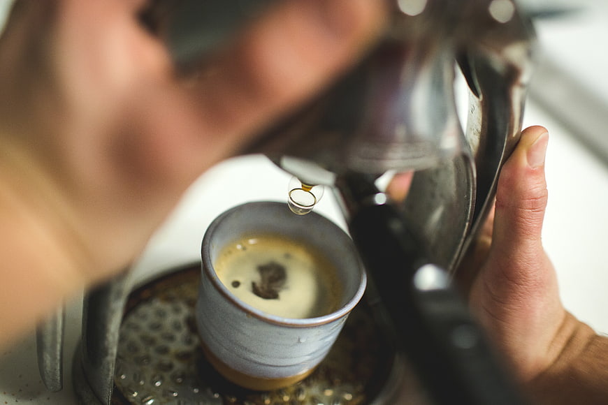 Close-up of espresso pouring into ceramic cup from moka pot