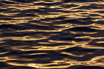 Golden sunset ripples on dark water surface texture