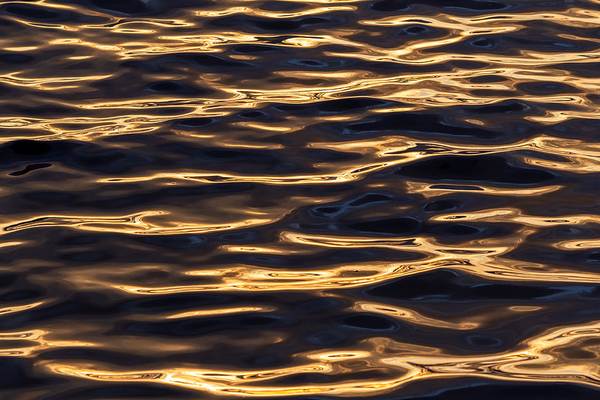 Golden sunset ripples on dark water surface texture