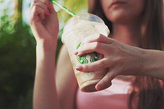 Woman holding iced Starbucks coffee drink outdoors