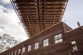 Low angle view of brick building under steel bridge structure