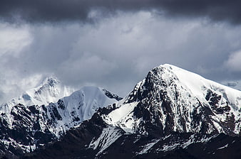 Snow-Capped Mountain Peaks Under Dramatic Stormy Clouds