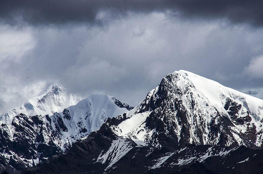 Snow-Capped Mountain Peaks Under Dramatic Stormy Clouds