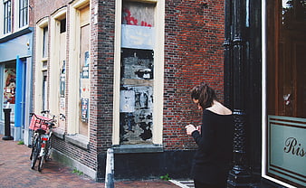 Woman texting on smartphone on urban brick sidewalk