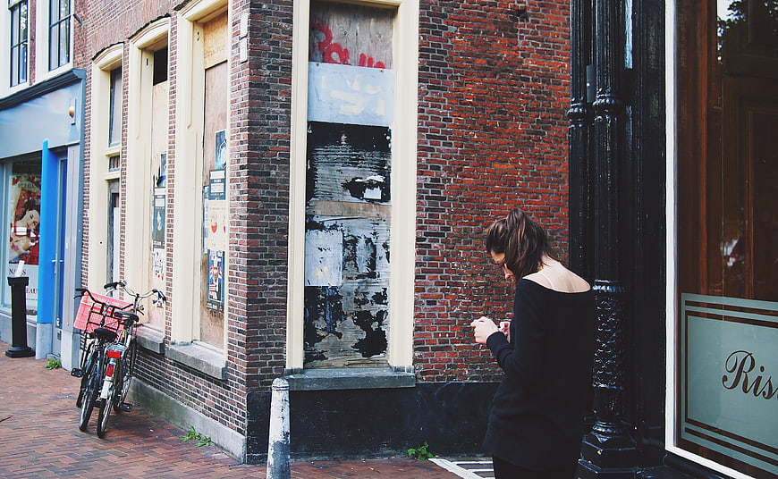 Woman texting on smartphone on urban brick sidewalk