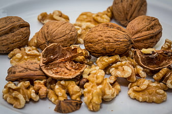 Close-up of whole and shelled walnuts on a white plate