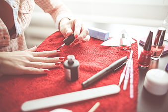 Woman applying red nail polish on red towel