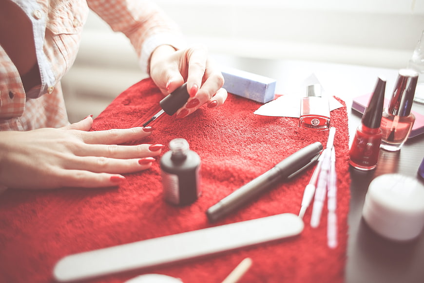 Woman applying red nail polish on red towel